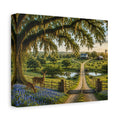 A rectangular canvas wall art print showing a pastoral rural landscape with a large mossy tree, blue flowers, deer, a dirt road, ponds, and small buildings in the distance, photographed against a plain white background.