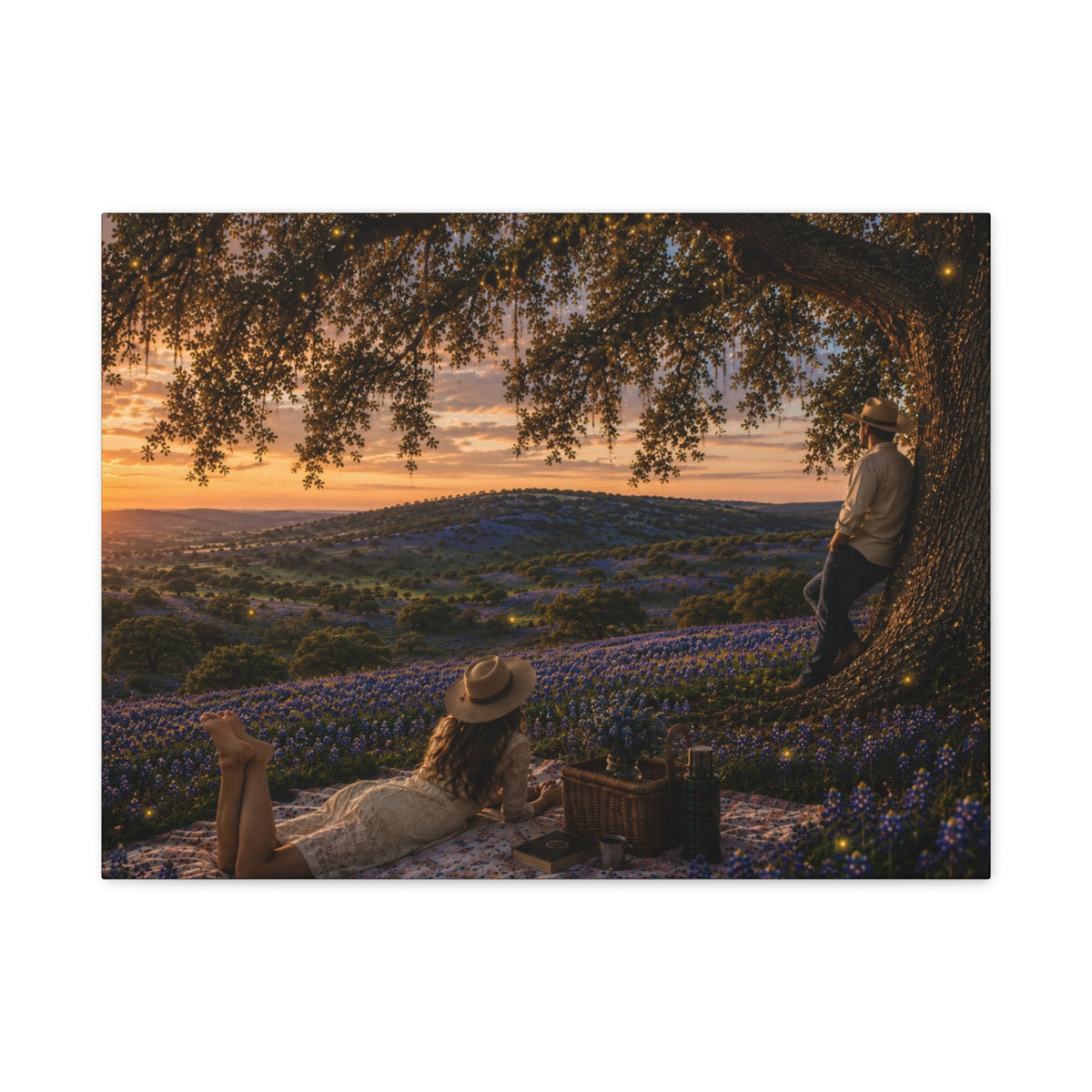 A rectangular wall art print or canvas showing a romantic outdoor picnic scene under a large tree at sunset, with bluebonnet flowers in the foreground and two people visible in the artwork. The print is photographed against a plain white background.