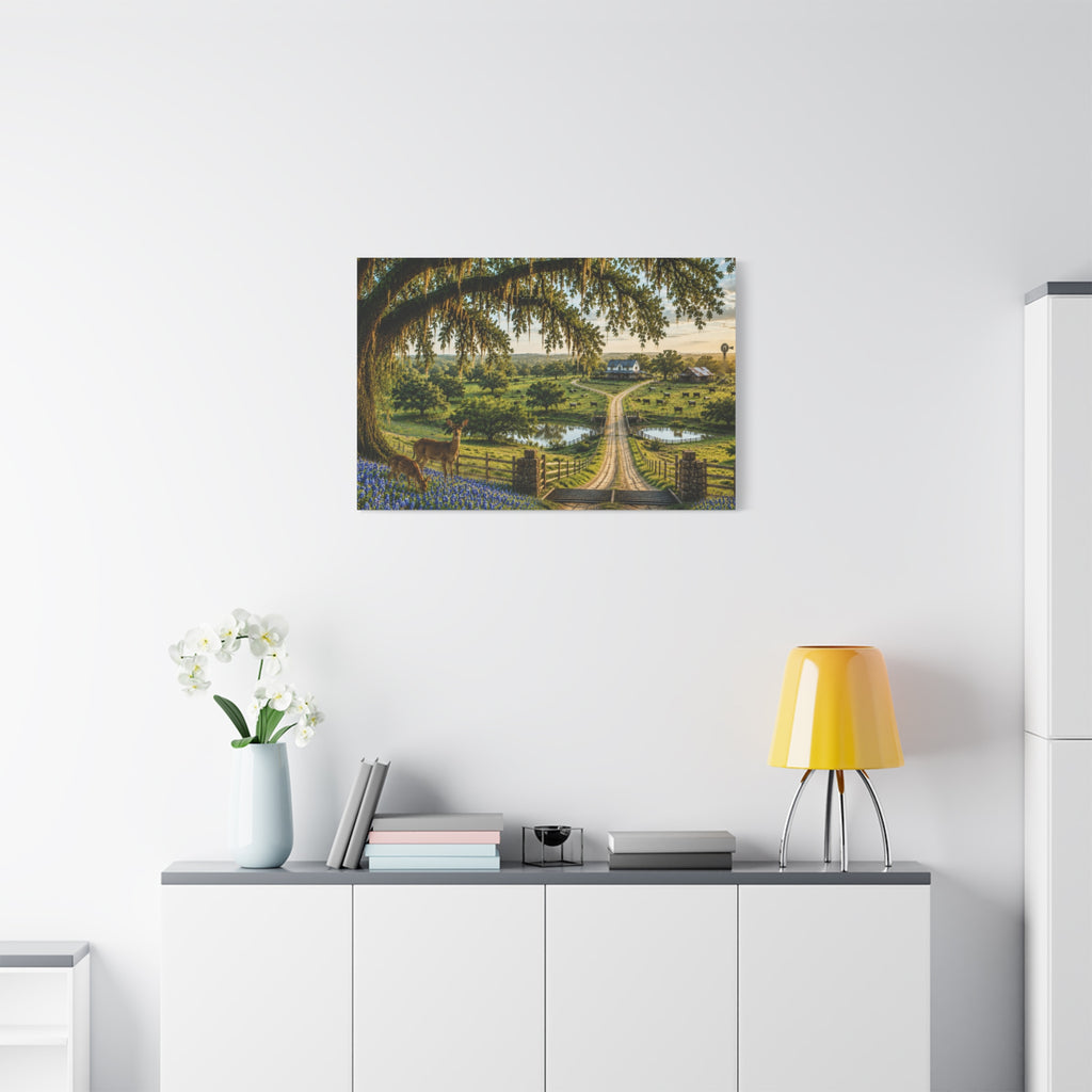 A framed landscape art print depicting a rustic wooden bridge over a green valley with trees and a sunset, displayed on a white wall above a modern white sideboard with a yellow lamp and white flowers.