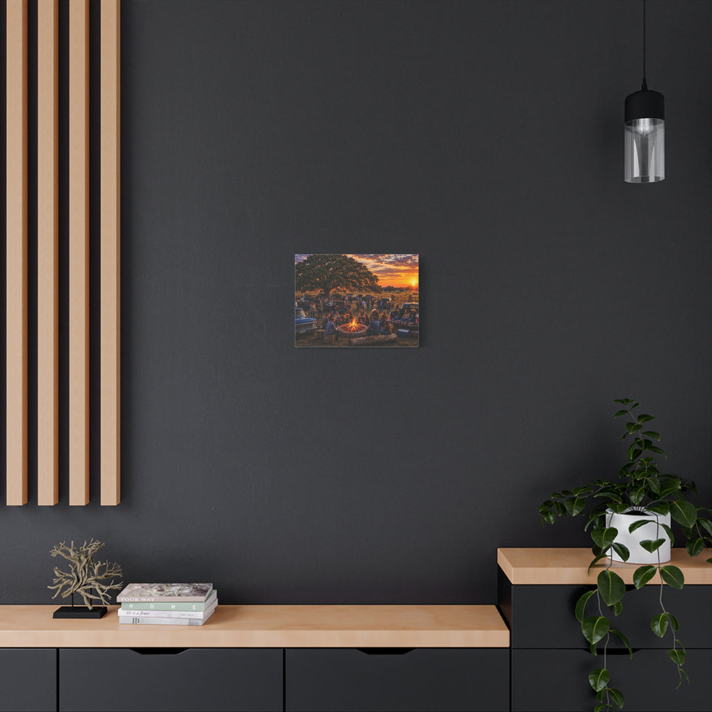 A square canvas art print depicting a scenic sunset over a forested hill with a lake, displayed on a dark gray wall in a modern room setting with a wooden console table, a potted plant, and a hanging light fixture.