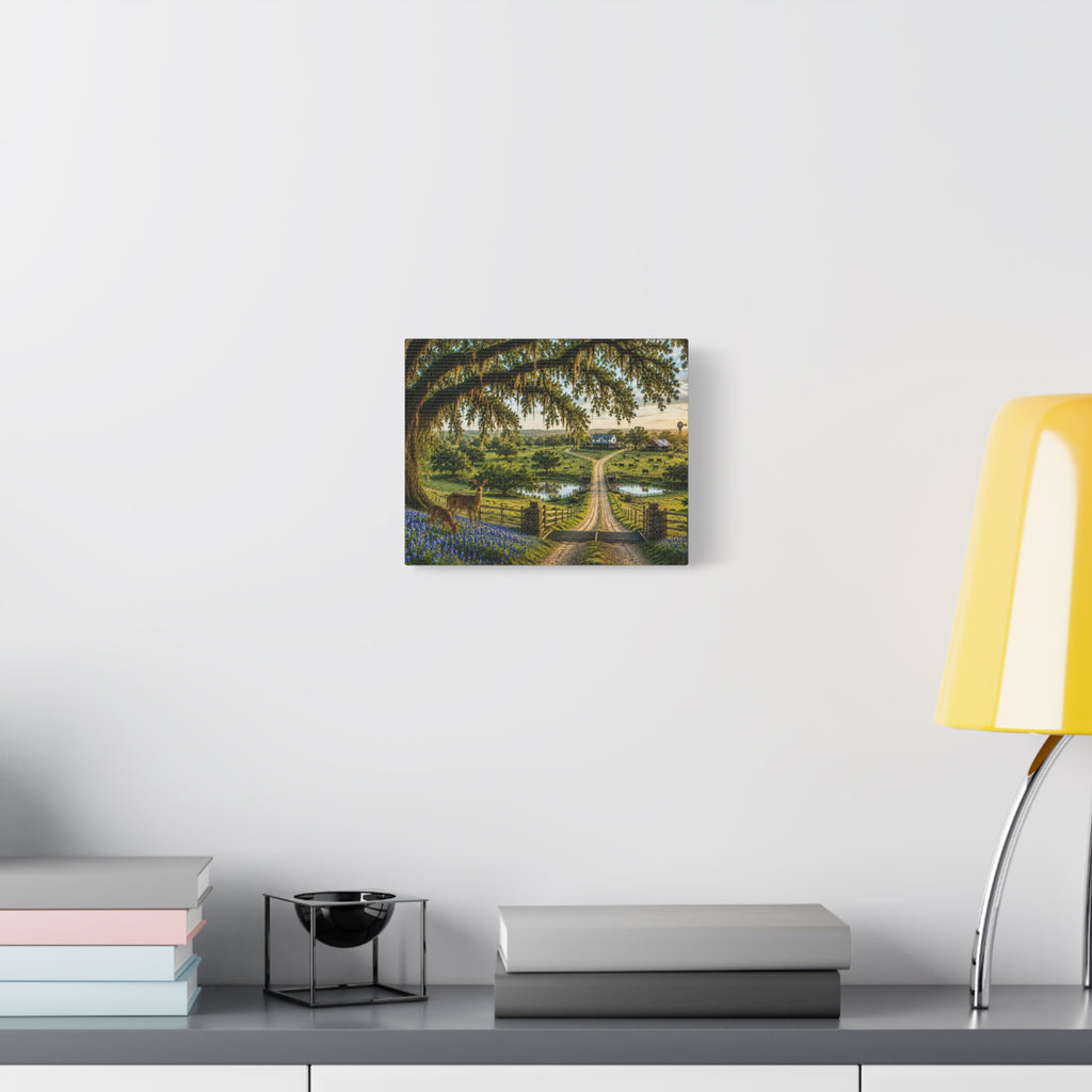 A small square wall art print showing a garden path under a large tree, displayed on a white wall above a shelf with books, a candle holder, and a yellow lamp.