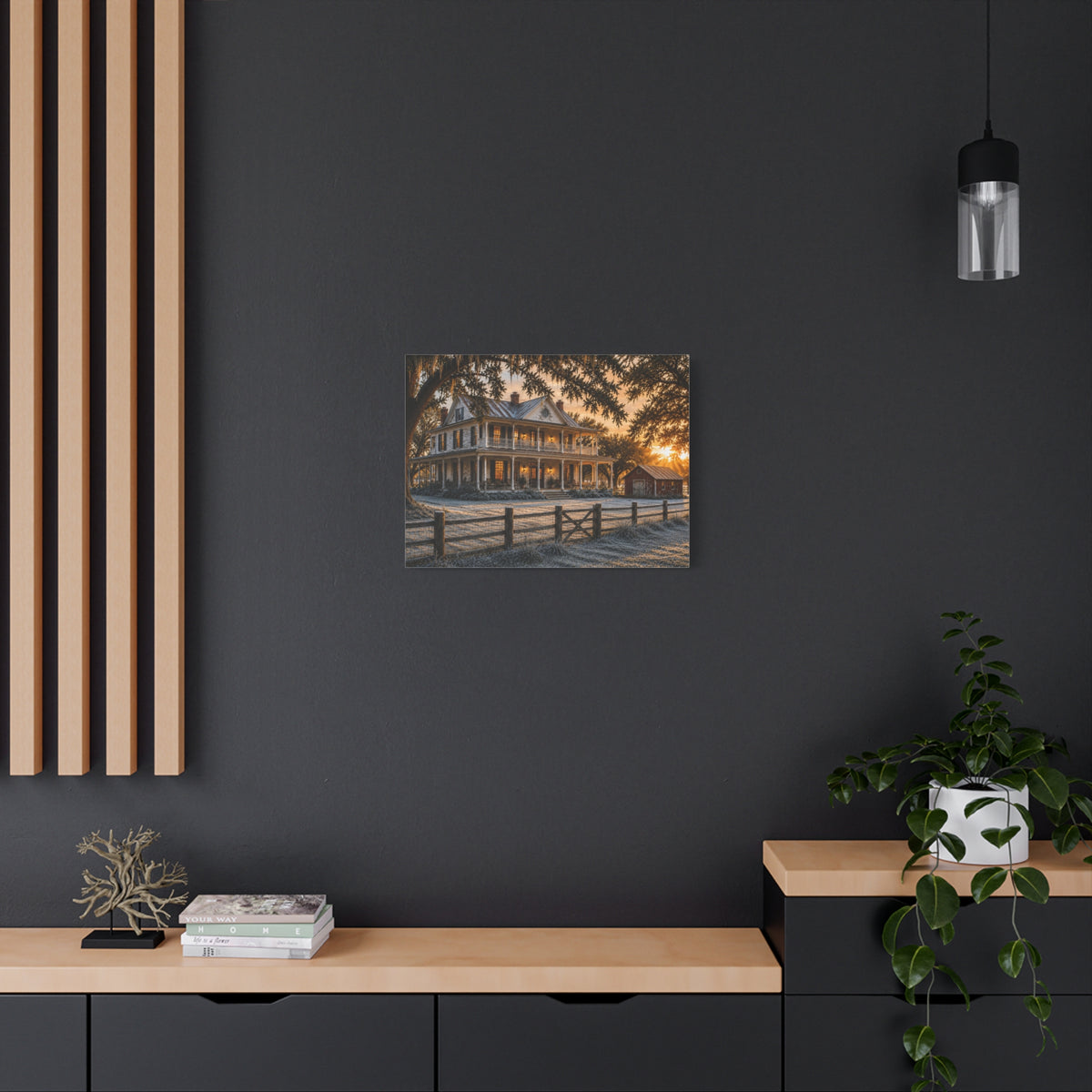 A First Frost canvas print showing a historic farmhouse, frosted yard, fence, and warm sunrise light, displayed on a dark wall with wooden shelves and decor.