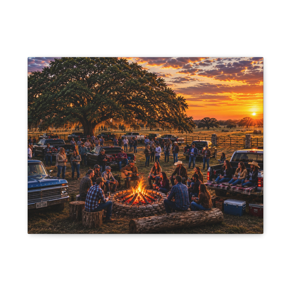 A rectangular wall art print or canvas showing a rustic outdoor campsite at sunset, with people gathered around a fire pit under a large tree, trucks, fences, and a warm orange sky. The print is photographed against a plain white background.